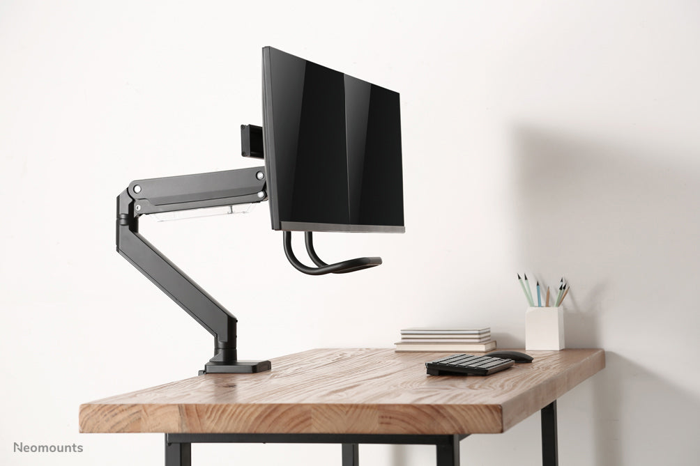 A Neomounts NM-D775DX fekete egy gázrugós asztali tartó keresztléc és kar segítségével legfeljebb 32 hüvelykes (81 cm) lapos képernyőkhöz.