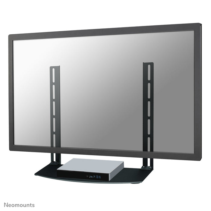 A Neomounts AV tartó, NS-SHELF100 modell, ideális AV eszközök elhelyezéséhez lapos képernyős tartók alatt.